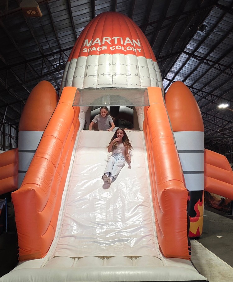 Emilia Hernandez, 12, of Battle Ground slides down the Mars Encounters bounce house mega structure, while Lilly Parker, 12, of Battle Ground waits her turn. The two were enjoying the opening day of the Clark County Fair