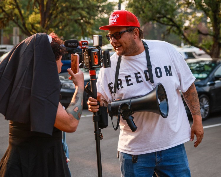 Area activist Fia Marie, left, responds to a counterprotester who singled out Marie while they were away from a crowd of a few dozen protesters who were against adding invocations to future regular council meetings on Monday, Aug. 3.
